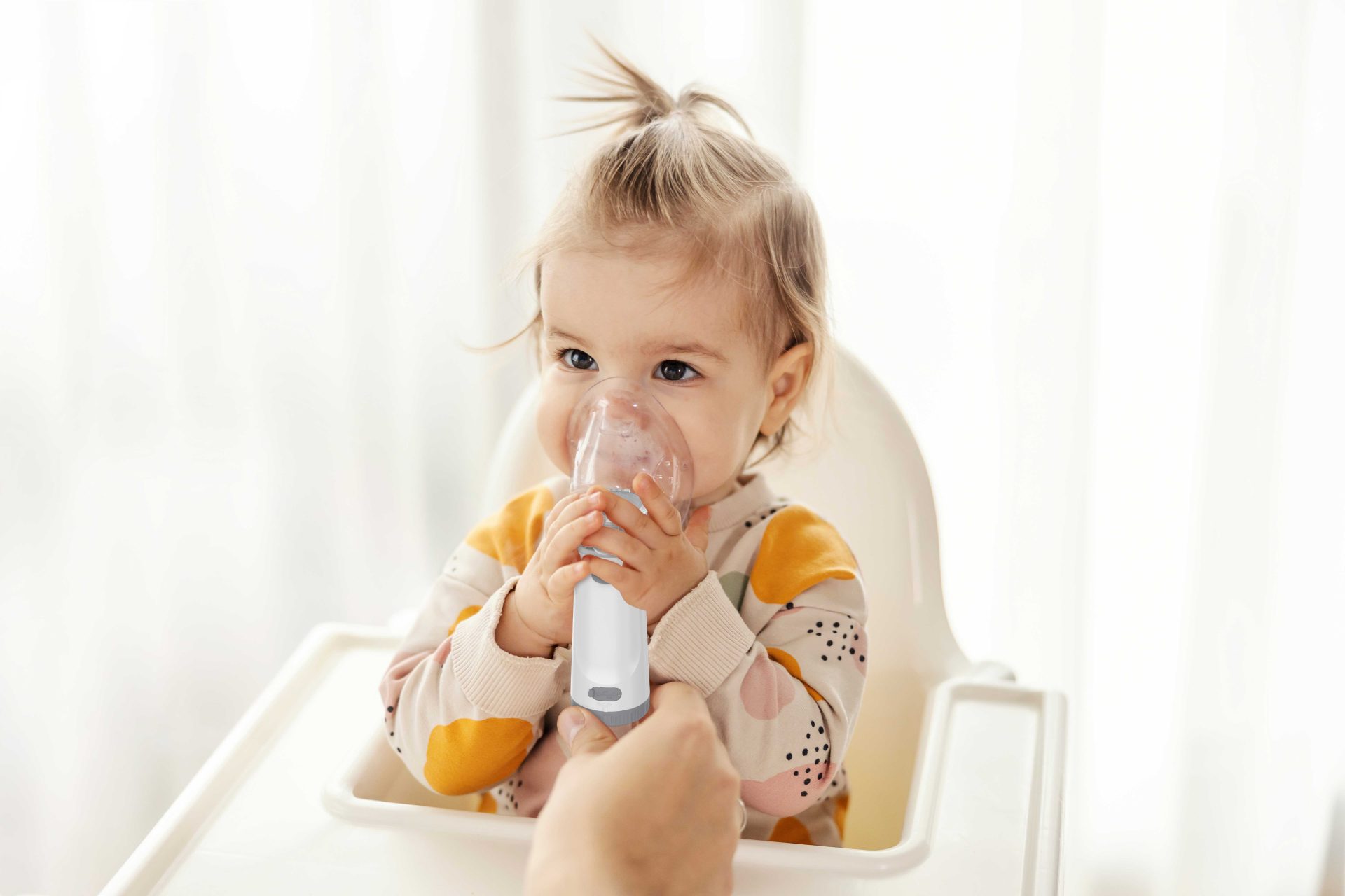 Young child using a portable mesh nebulizer with an adult's assistance